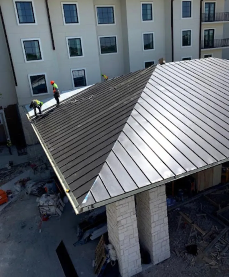 Crew installing standing seam metal roof panels on a commercial project in Eufaula